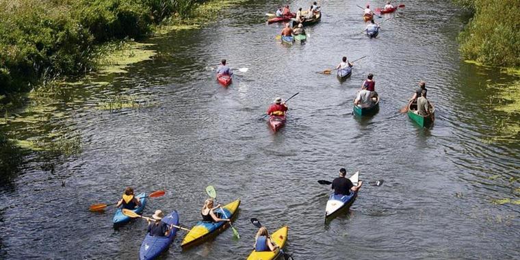 Eine Gruppe von Kayakfahrern gleiten über einen Fluss im Aller-Leine-Tal.