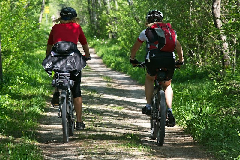 Zwei Frauen fahren mit dem Mountain-Bike einen Weg entlang.