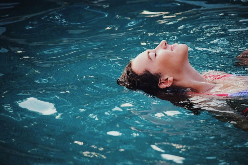 Eine Frau gleitet mit geschlossenen Augen im Wasser.